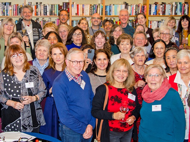 Large group of Centrepoint volunteers in the library looking at the camera and smiling