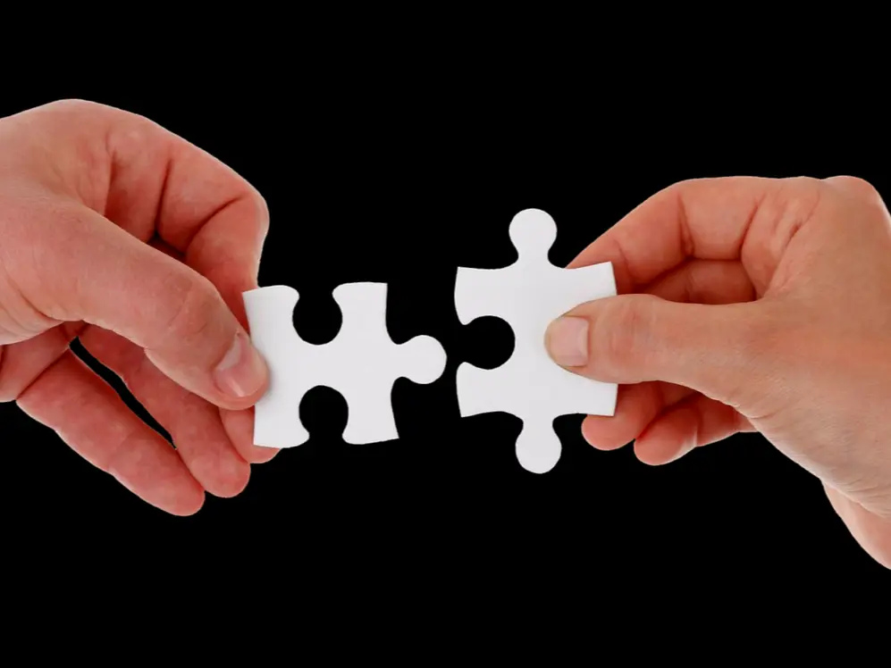 two hands holding two pieces of connecting jigsaw